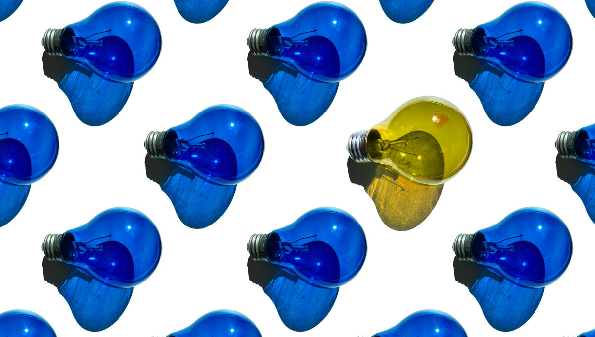 One yellow light bulb among many blue light bulbs on a white background.