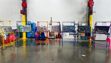 Seven different colored (yellow, green, orange, red, blue, black, and purple) Flex Craft Shadow Box Tool Carts sitting side-by-side on the manufacturing production floor.